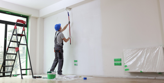 Finition-chapo.jpeg (Male painter paints house wall with roller brush.)