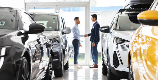 Intersectorielle véhicules 2-chapo.jpeg (Customer and sales assistant shaking hands, car showroom interior)