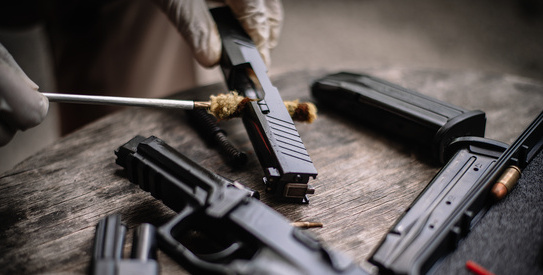 Image 29-particulier_chapo-AdobeStock_521412868.copy-crop543x275.jpeg (The gunsmith is sitting around cleaning the gun and disassembling and maintaining the pistol.)